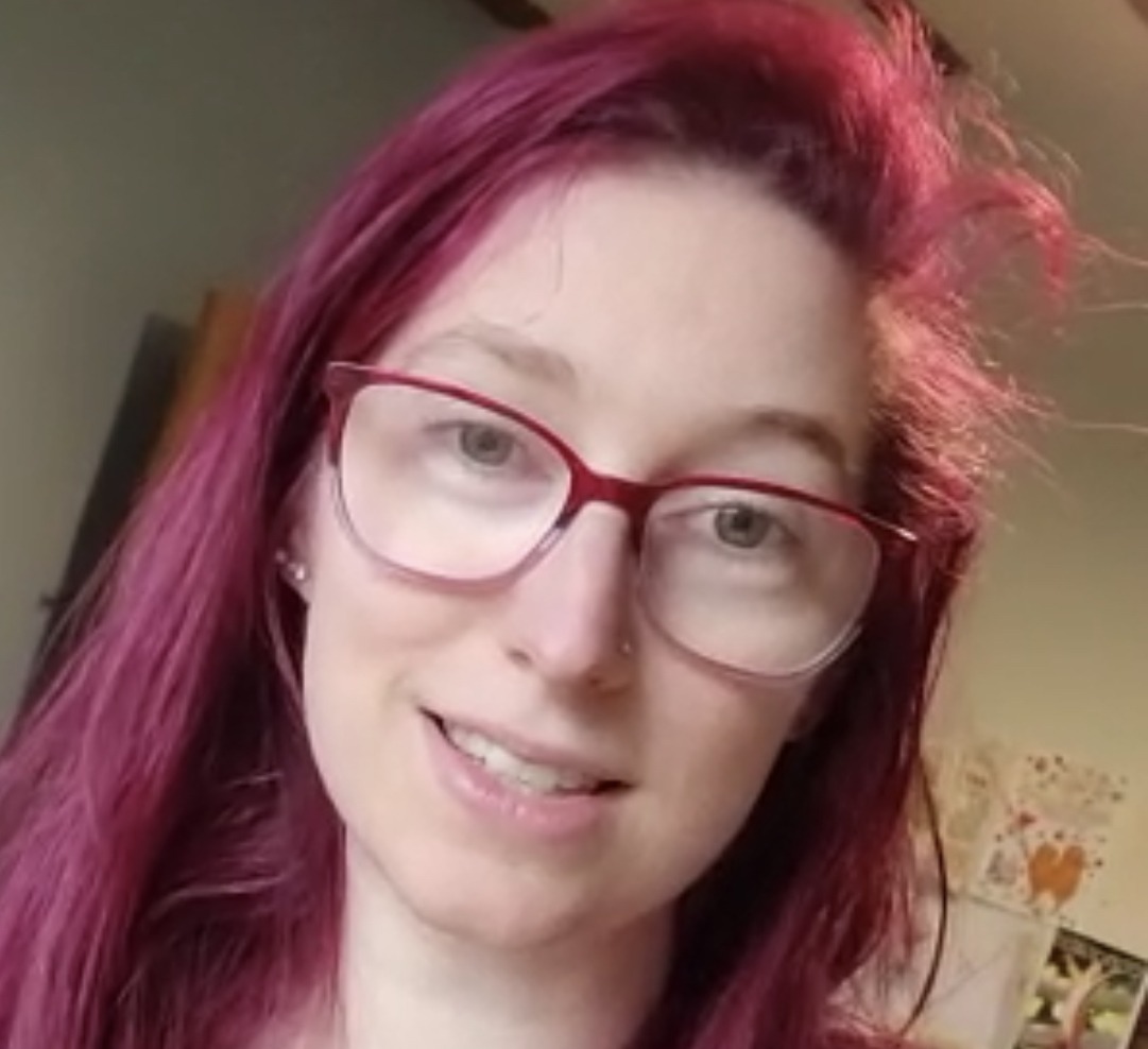 A woman with red hair and glasses