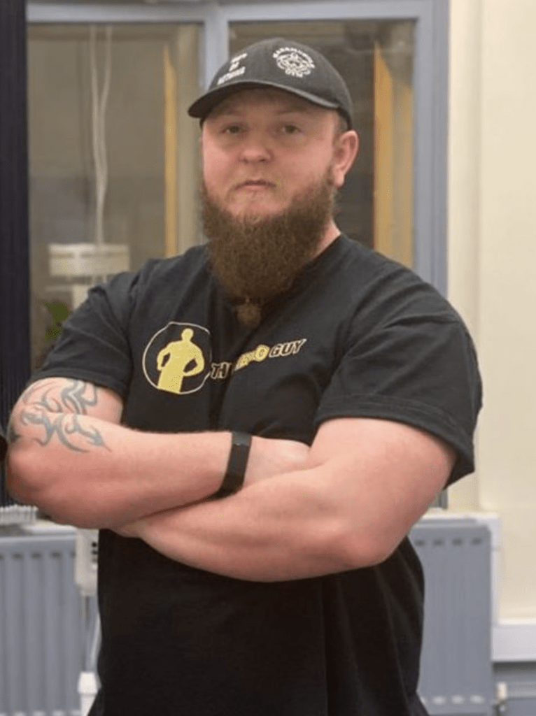 A man with his arms folded, wearing a beard and a hat.