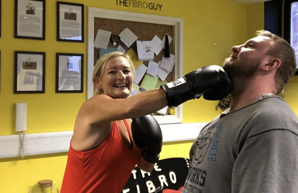 A woman jokingly hotting a man wearing a boxing glove
