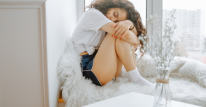 A woman in a flare up comforting herself on a couch