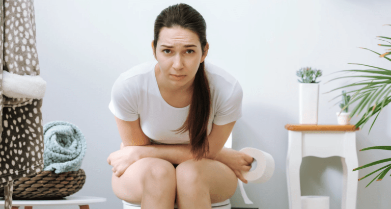 A woman sat constipated on the toilet