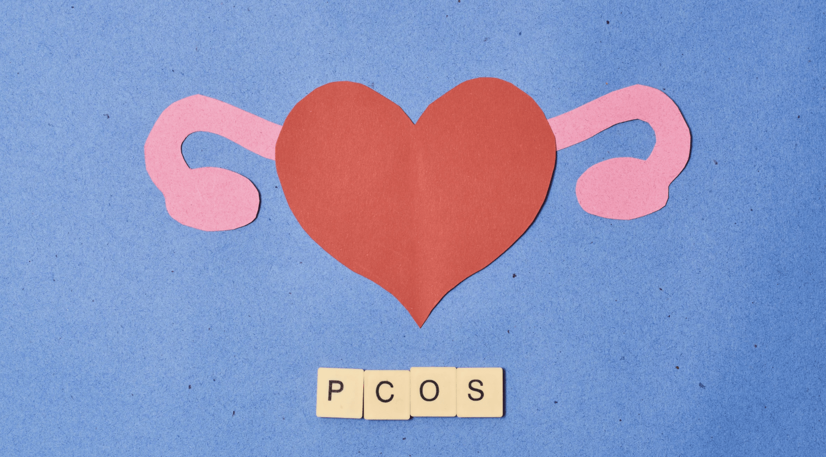 A hear with ovaries and scrabble tiles underneath reading PCOS